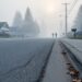A quiet residential street in Sicamous obscured by smoky haze, with indistinct silhouettes of people in the distance.