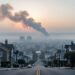 Hazy town skyline with drifting wildfire smoke in the sky, suggesting how wind and weather affect air quality.